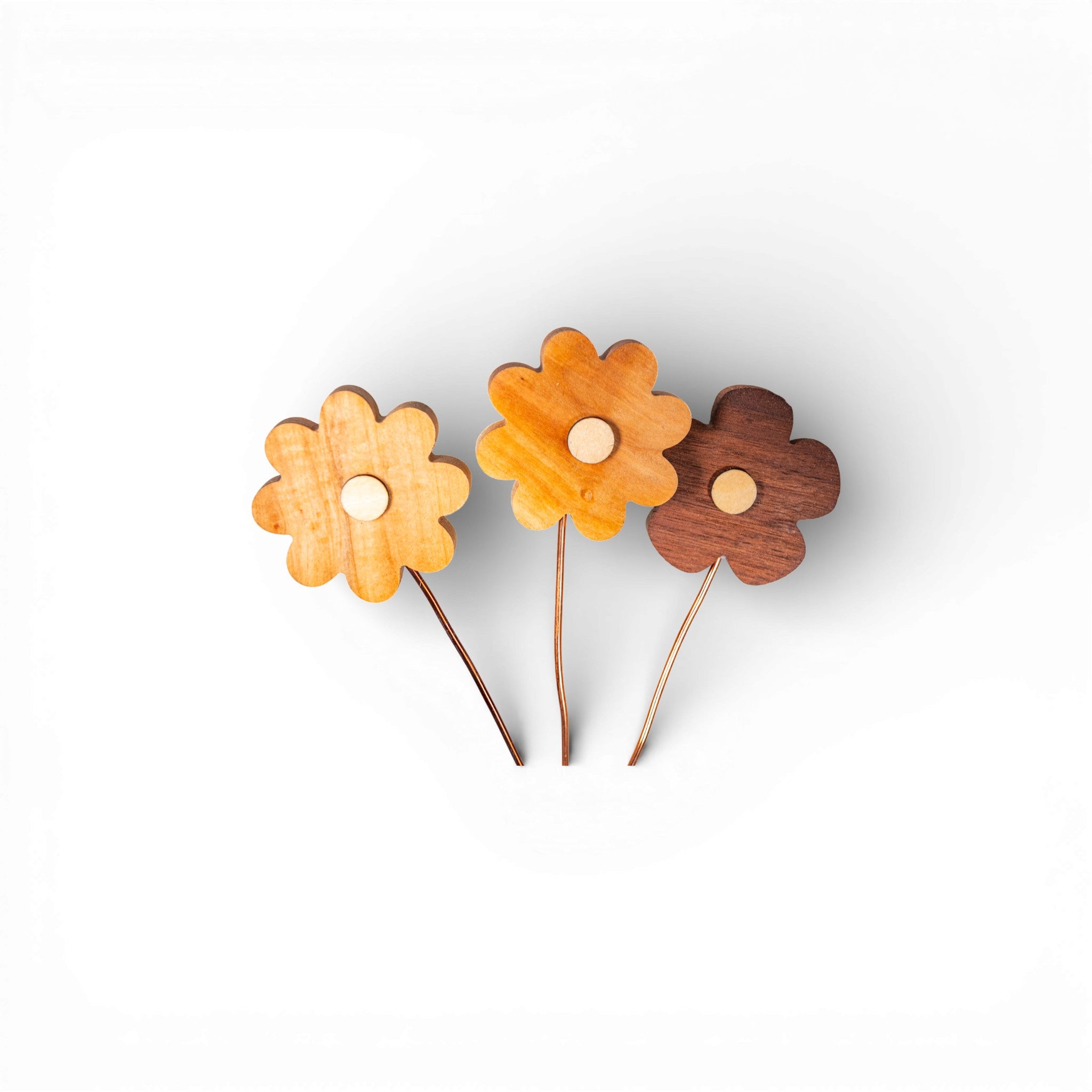 Flat lay of wooden daisy components with copper wire stems and visible wood texture
