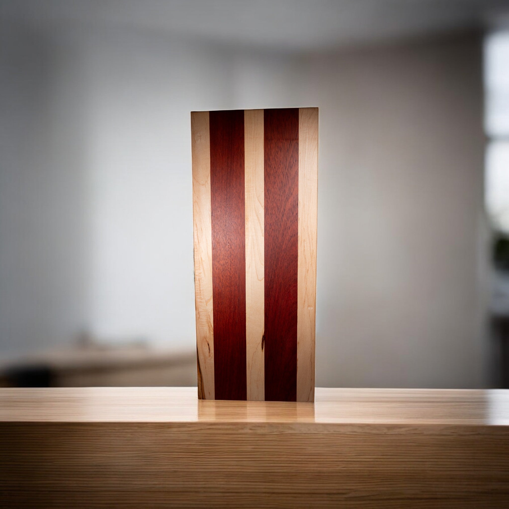 Upright maple padauk wood serving board on wooden surface