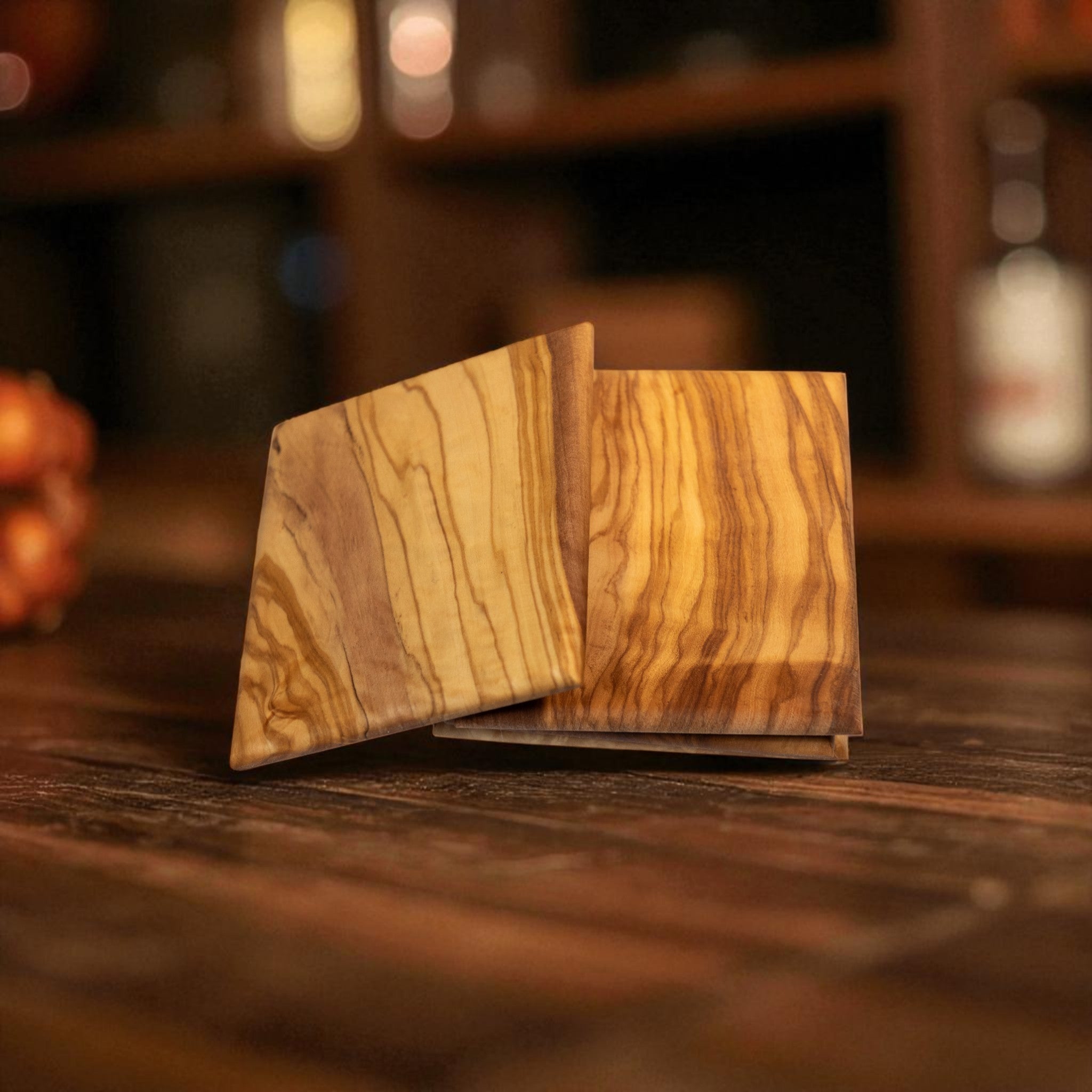 Set of 4 olive wood coasters with natural grain on dark surface