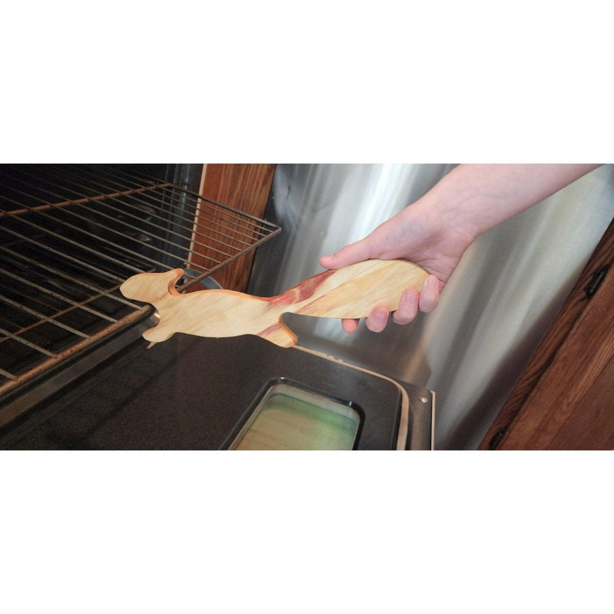 Light wood squirrel oven rack puller hooking onto hot oven rack