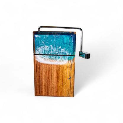 Front view of handcrafted wood and resin ocean wave cheese slicer with metal lever