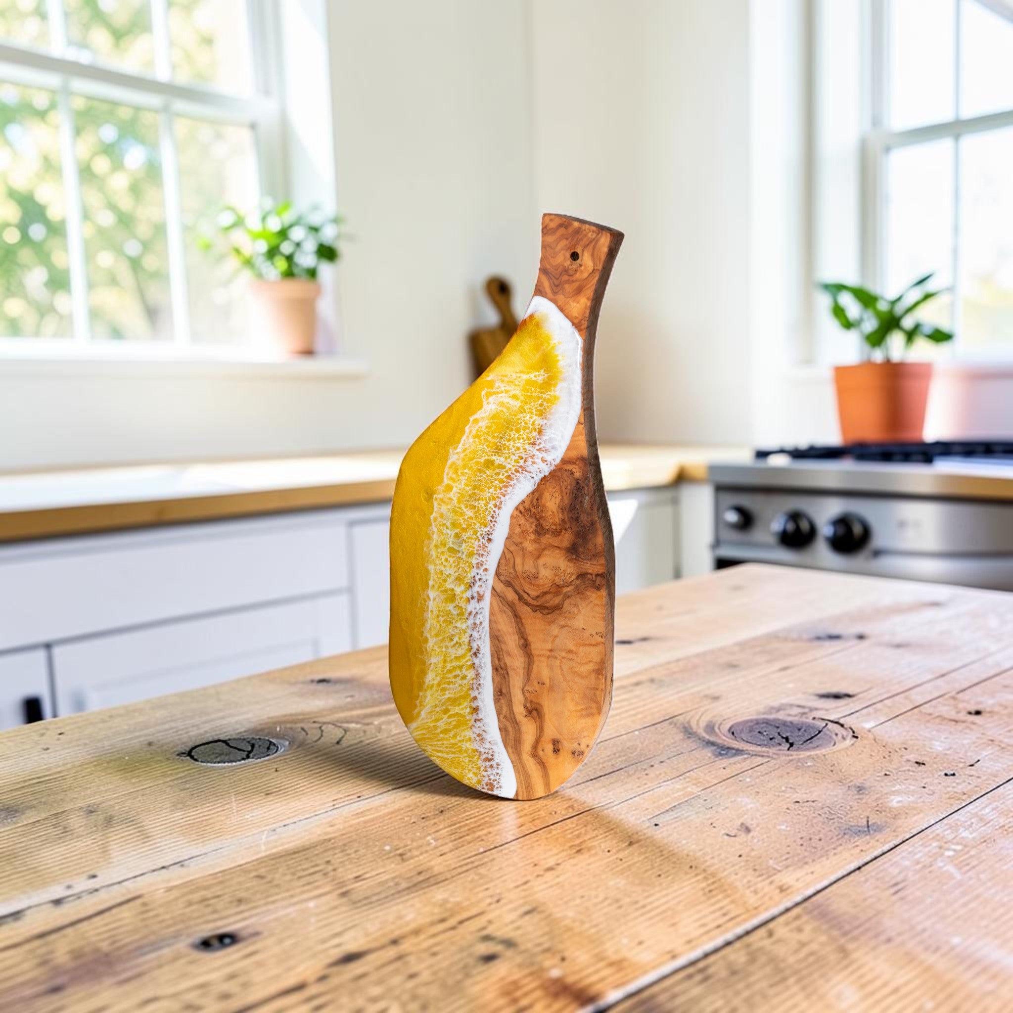 Handcrafted yellow ocean wave olive wood charcuterie board on kitchen counter