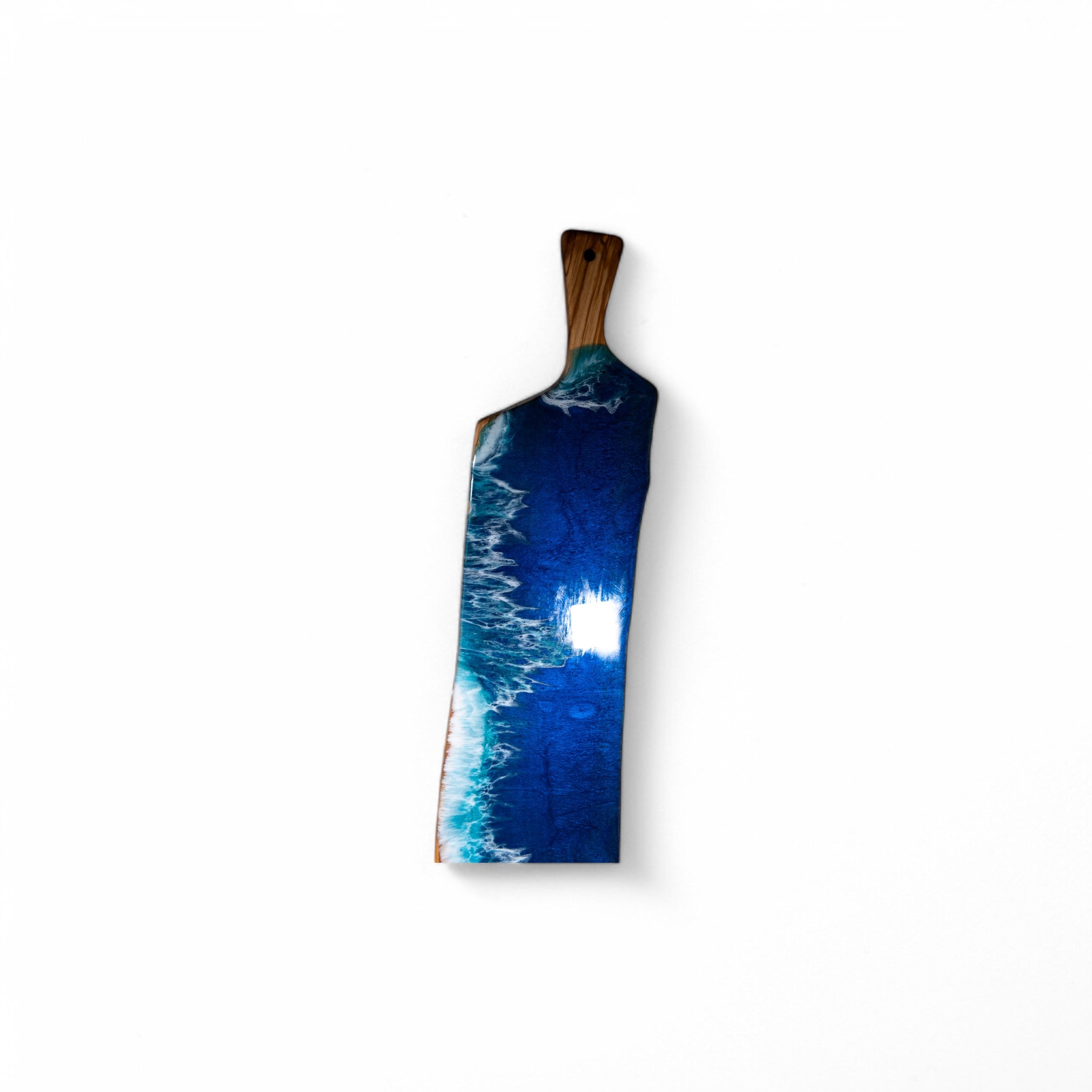 Olive wood charcuterie board with blue resin ocean wave design and natural handle