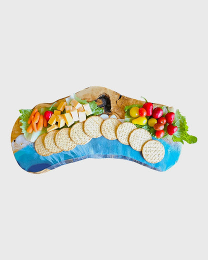 Wooden serving platter styled with cheese crackers and vegetables