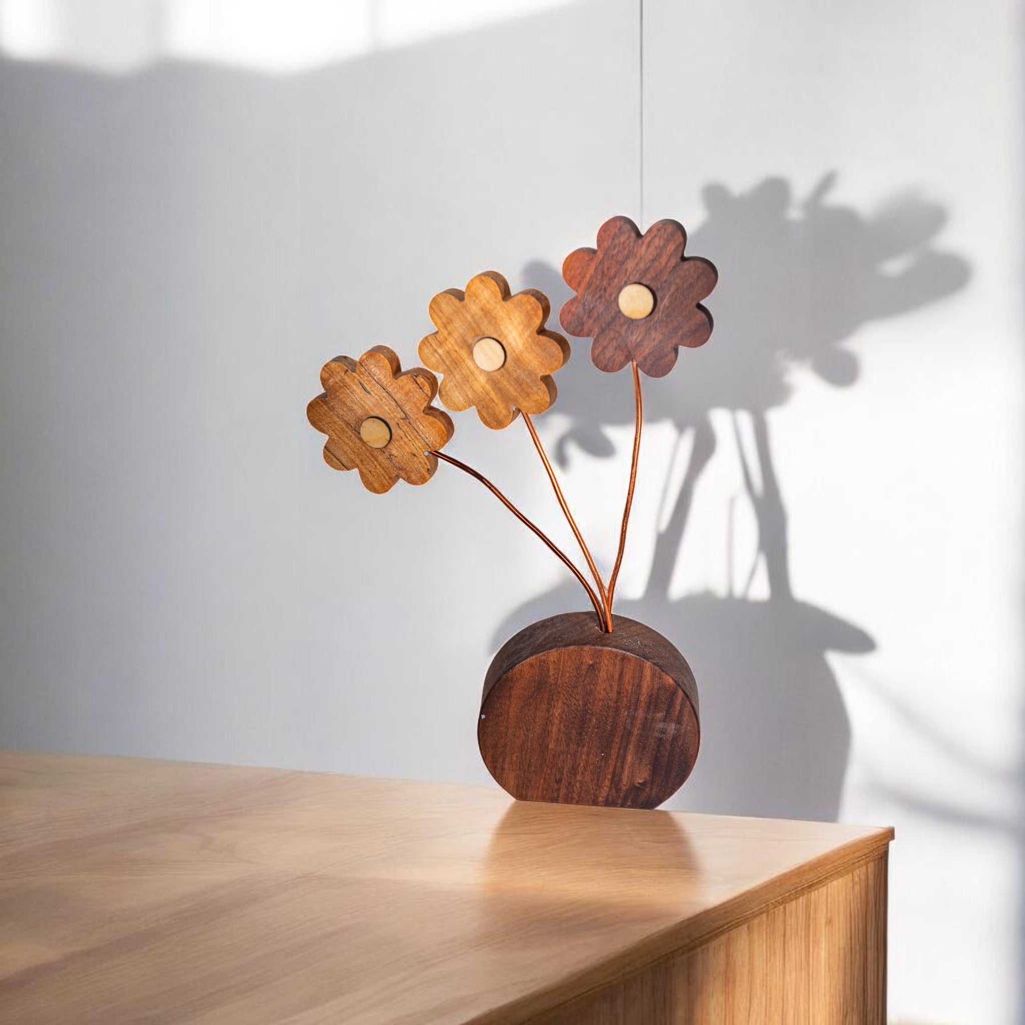 Wooden daisy flower decor on light wood surface with shadow