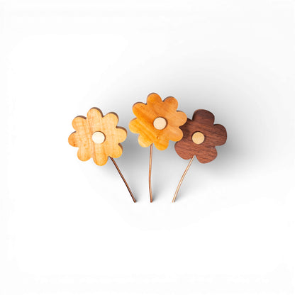 Close-up of three separate wooden daisy flowers showing scalloped petals and natural grain