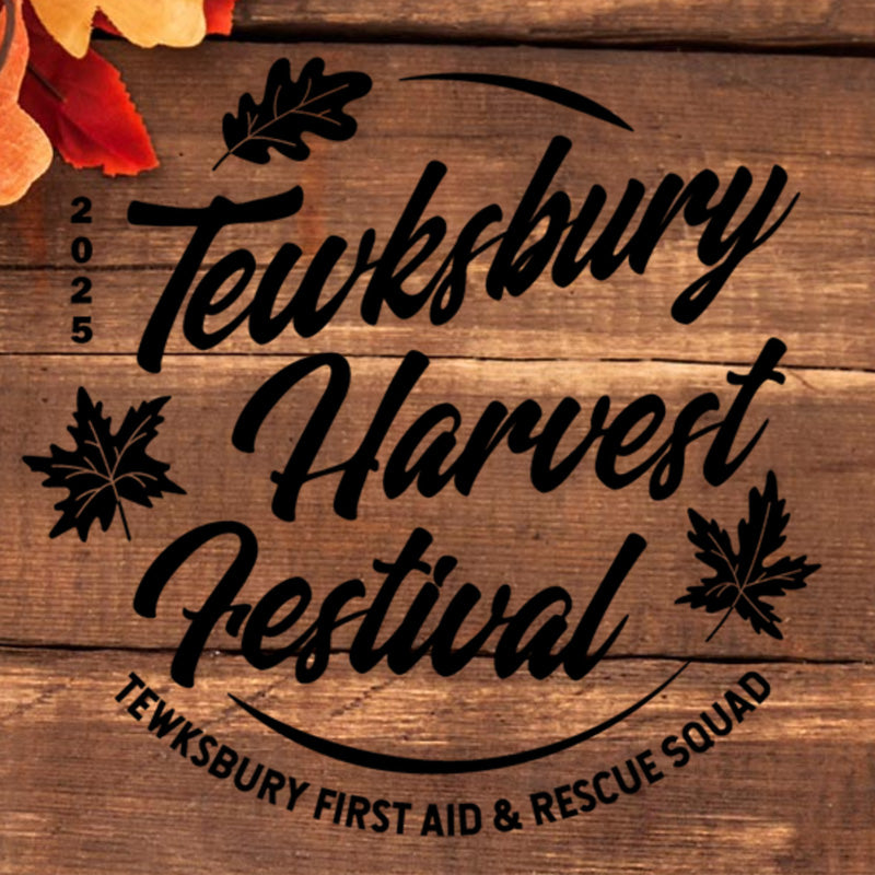 Wooden sign with 'Tewksbury Harvest Festival' text and leaf designs on a wooden background.