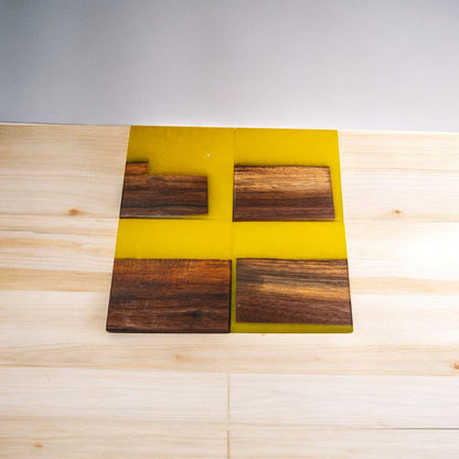 Four square walnut and yellow epoxy coasters showing unique wood grain patterns